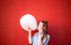 Girl eating cotton candy on a red background
