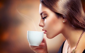 Девушка с закрытыми глазами наслаждается кофе