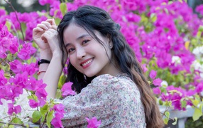 Smiling asian girl on a background of pink flowers