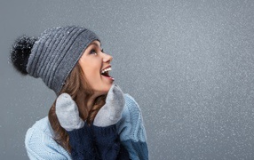 Smiling girl in warm hat on gray background