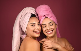 Две девушки с полотенцами на голове на красном фоне 