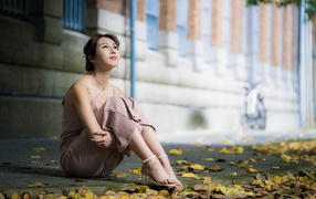 Young asian girl sitting on the ground with leaves