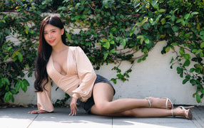 Молодая девушка азиатка с длинными волосами лежит на земле у стены 