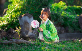 Молодая азиатка в кимоно сидит в парке