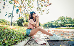 Молодая азиатка сидит на земле в осеннем парке