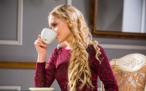 Young beautiful girl drinking coffee from a white cup