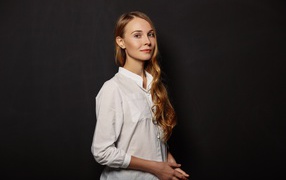 Молодая девушка в белой рубашке на фоне черной стены 