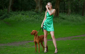 Молодая девушка гуляет с собакой в парке