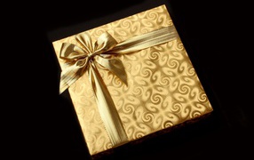 Golden packaging with a gift on a black background