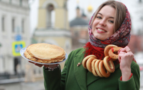 Smiling girl with pancakes and bagels on Shrovetide