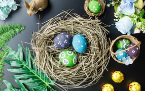 Яркие пасхальные яйца на столе в гнезде