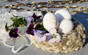 Three white eggs in a willow wreath for Easter