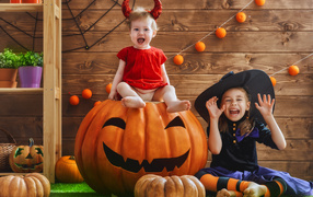 Two little girls with pumpkin in Halloween costumes