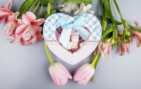 Heart shaped box of chocolates and flowers on a gray background on March 8