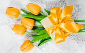 Yellow tulips with a gift for March 8 for a girl