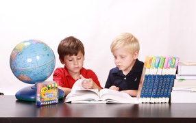 Two schoolboy boys with books and a globe at the table
