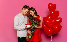 Loving couple with balloons on pink background