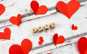 Red hearts and the inscription love on a wooden table