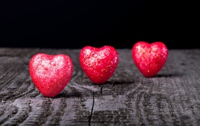 Shiny red hearts on a wooden table