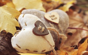 Два сердца из ткани лежит на земле с листьями 