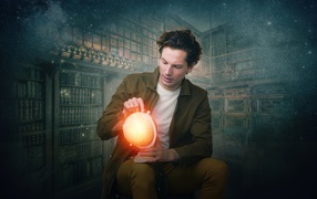 A man in an old library with a glowing globe in his hand