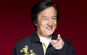 Улыбающийся мужчина, актер Джеки Чан на красном фоне