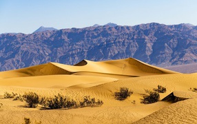 Красивые песчаные дюны у гор под голубым небом 