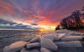 Blocks of ice lie on the seashore at sunset