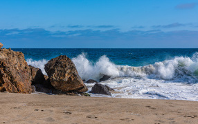 White sea waves hitting large stones on the shore