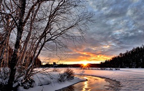 Покрытые снегом берега реки на рассвете зимнего солнца
