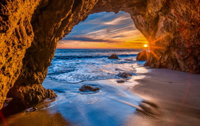 Sunset in a stone arch in the sea