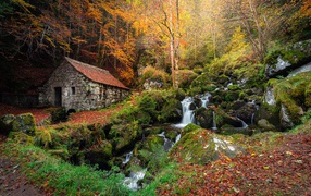 Old stone house in an autumn park with a waterfall