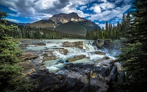 Waterfall flows down the stones against the backdrop of a mountain, Canada