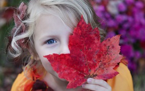 Маленькая девочка закрывает лицо листом