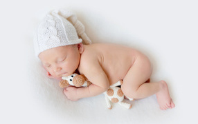 Baby in a hat with a toy on a white background