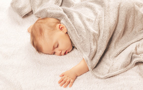Грудной спящий ребенок под одеялом 