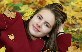Красивая голубоглазая девочка лежит на опавшей листве