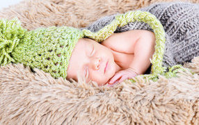 Beautiful sleeping nursing baby in a knitted suit