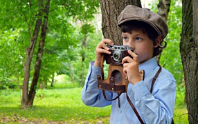 Мальчик с фотоаппаратом в руках в парке
