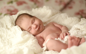 Cute nursing baby sleeping on a white bedspread