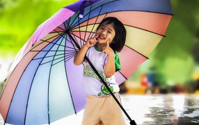 Маленькая девочка азиатка под большим разноцветным зонтом 