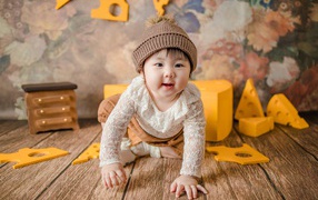 Маленький азиатский ребенок на полу с игрушками