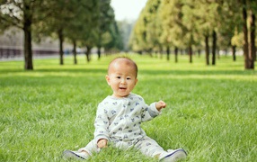 Little asian child sitting on green grass
