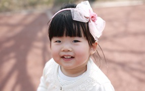 Маленькая девочка азиатка с бантом на голове 