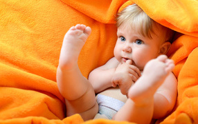 Маленький голубоглазый ребенок в желтом покрывале 