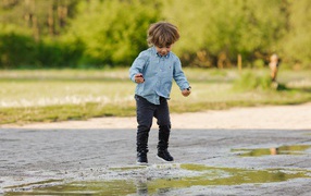 Little boy jumping through puddles
