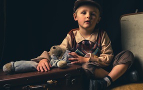 Маленький мальчик с чемоданом и игрушкой