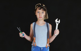 Little boy with tools in hands on black background