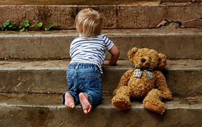 Маленький ребенок с медведем на ступеньках