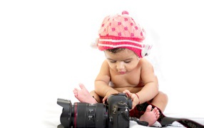 Маленький ребенок с фотоаппаратом на белом фоне 